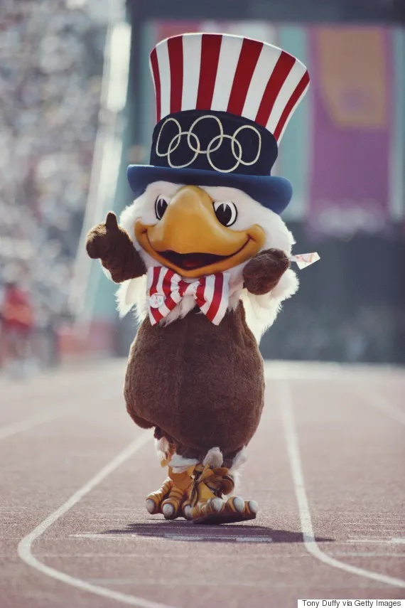 Botarga de un águila calva con sombrero representando a USA caminando por una pista de atletismo