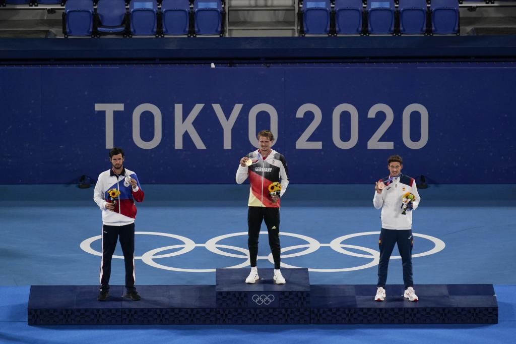 Ganadores del primero, segundo y tercer lugar de una competición en las olimpiadas presentando sus medallas en el podio 